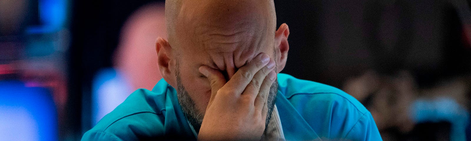 A photo of a trader wiping his eyes as he watches stock prices at the New York Stock Exchange.