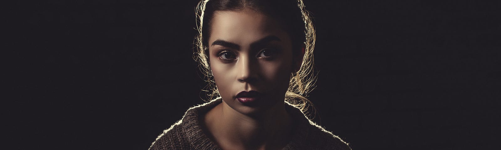 Portrait of a young woman against a black background.
