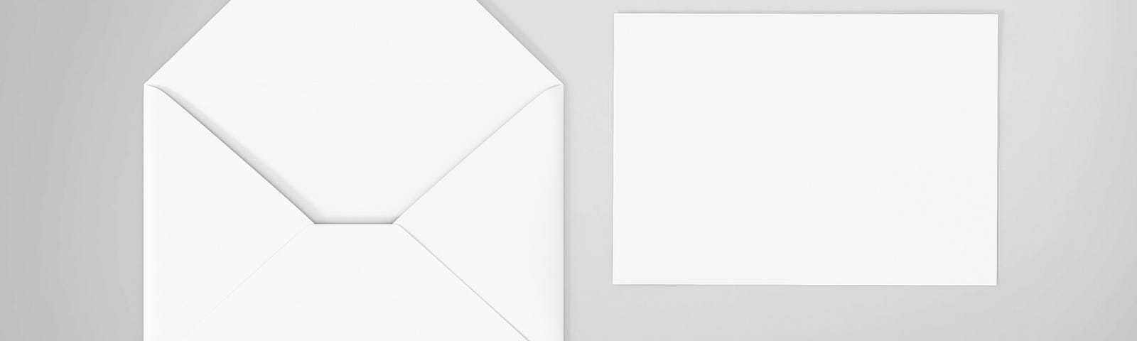 A white card envelope with a blank piece of note paper beside it.