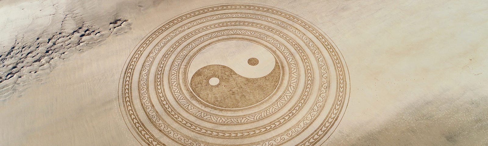 Ying and yang symbol on a beach, with the sea coming in