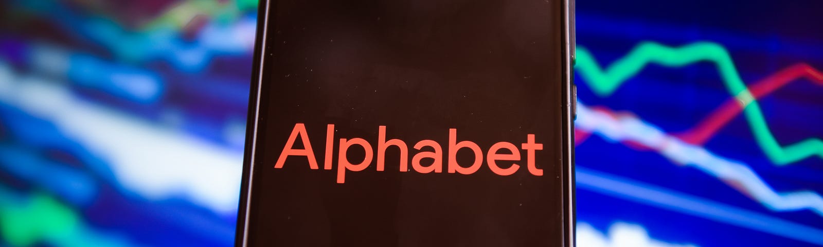 In this photo illustration an Alphabet logo seen displayed on a phone against a background illustrating the stock market.