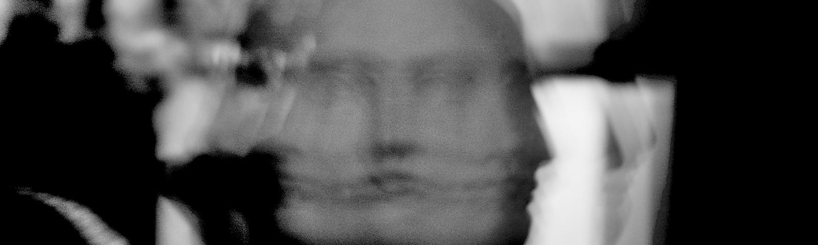 Black and white superimposed image of a sculpture of a face.