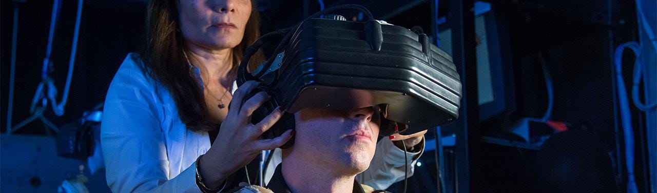 A lab technician places a VR headset onto someone’s head.