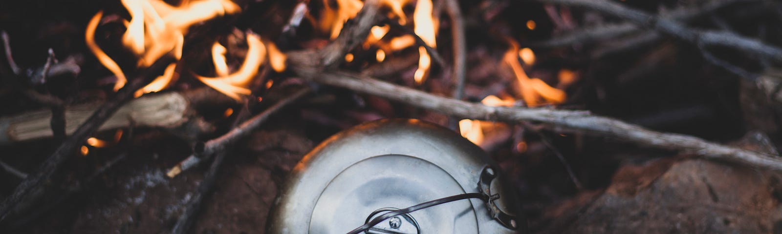 Outdoors burning fire with a kettle warming