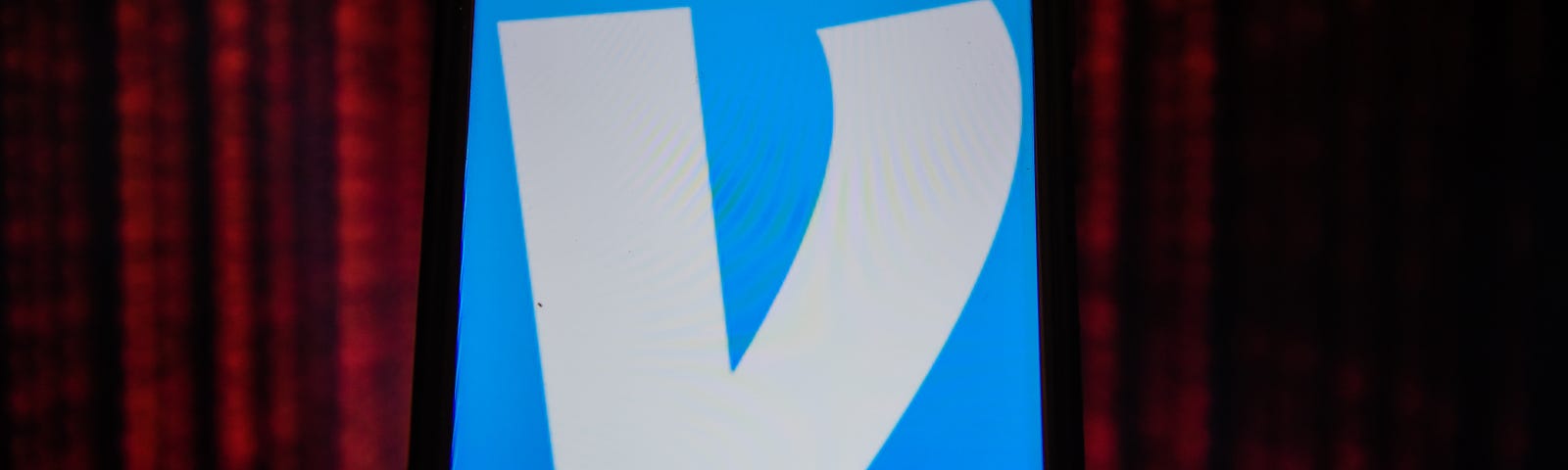 A logo of Venmo displayed on a phone screen against a dark red background, signifying privacy, technology, and transactions.