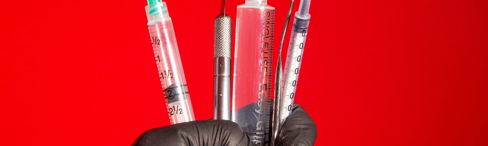 A graphic featuring a hand holding syringes.