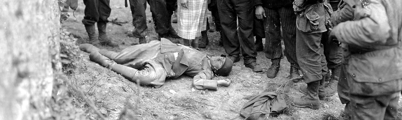 French civilians greet American invasion forces. A dead German lies at their feet, ignored.