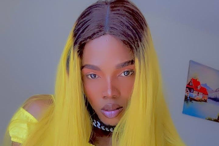 LGBTQ+ Activist Roxy in a yellow wig, silver chain & yellow top