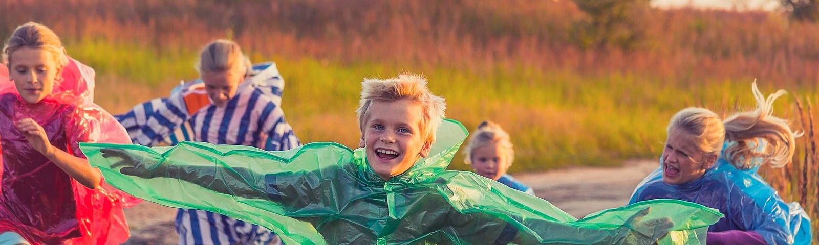 Children are wearing colored raincoats while running on a dirt road to depict the runner-ups for the Medium Writing Challenge honorable mentions.