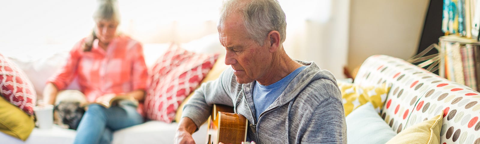 An older man learning guitar by watching an online tutorial on his tablet.