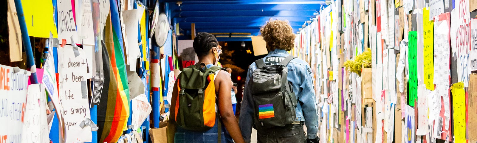 Two activists walking down a hallway covered with signs.