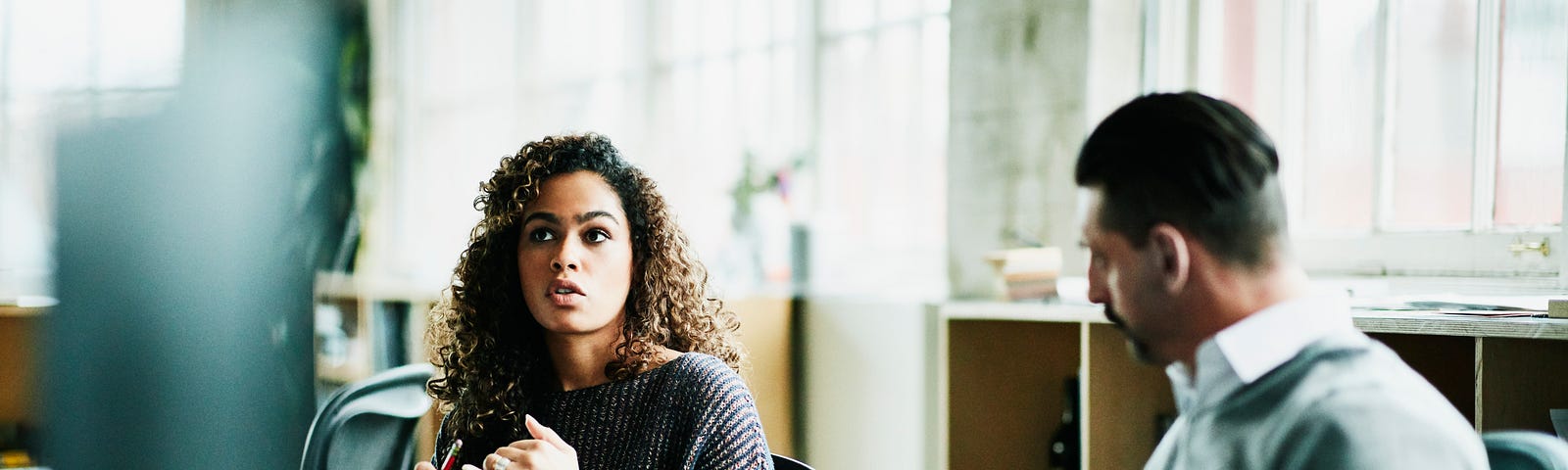 A woman discusses her idea in a meeting with a male colleague.