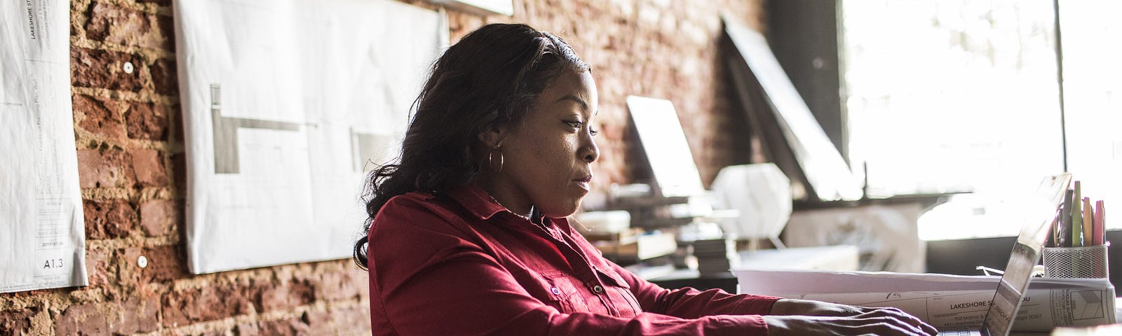 A Black businesswoman in a wheelchair works at her desk.