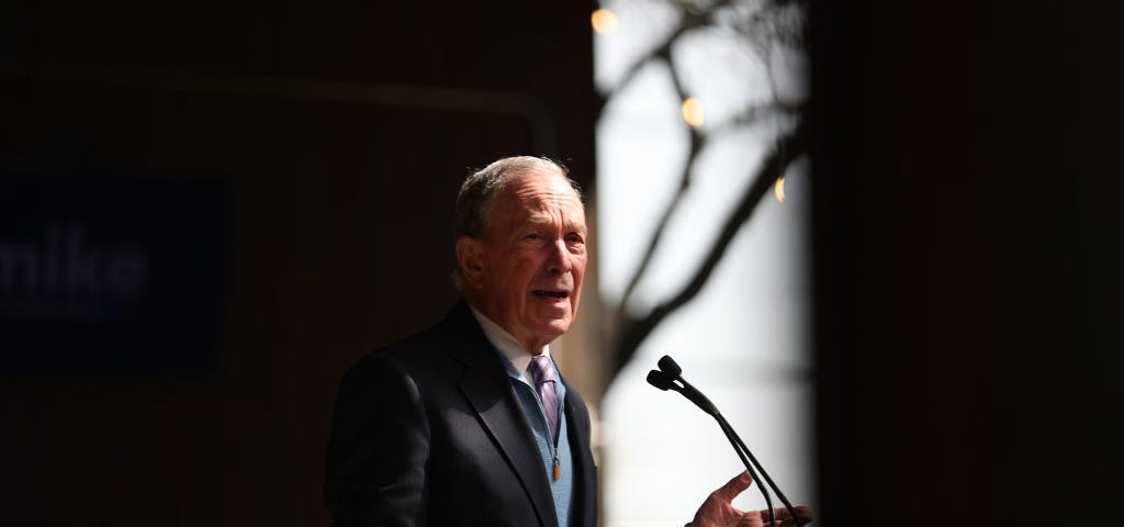 A photo of Mike Bloomberg speaking at a rally.