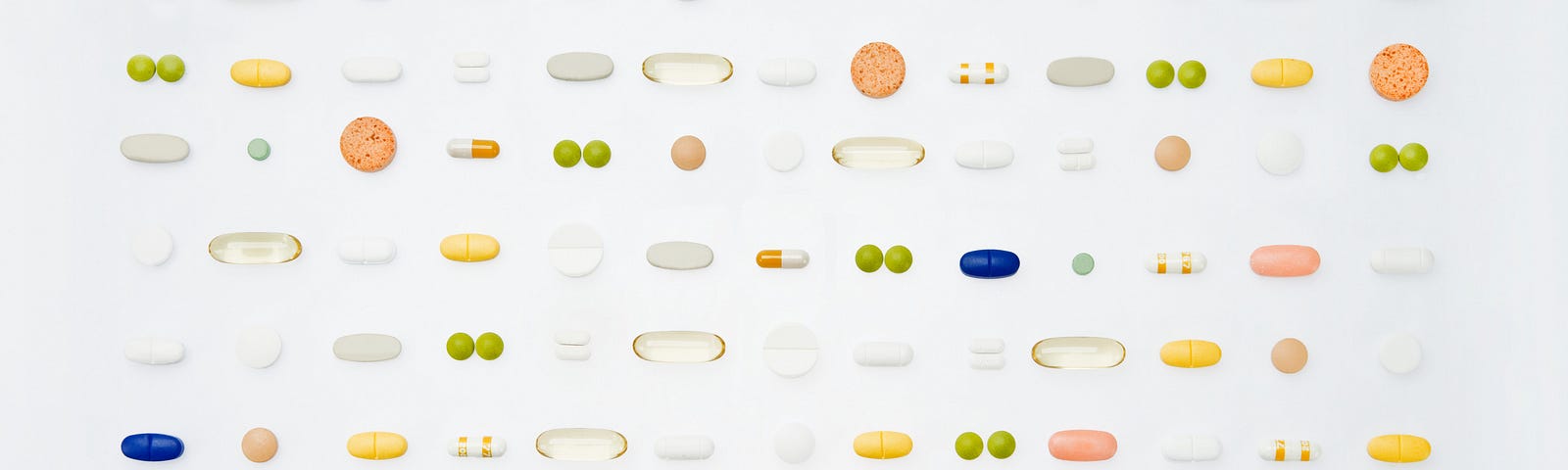 A variety of different pills and supplements are laid out in a grid against a white backdrop.