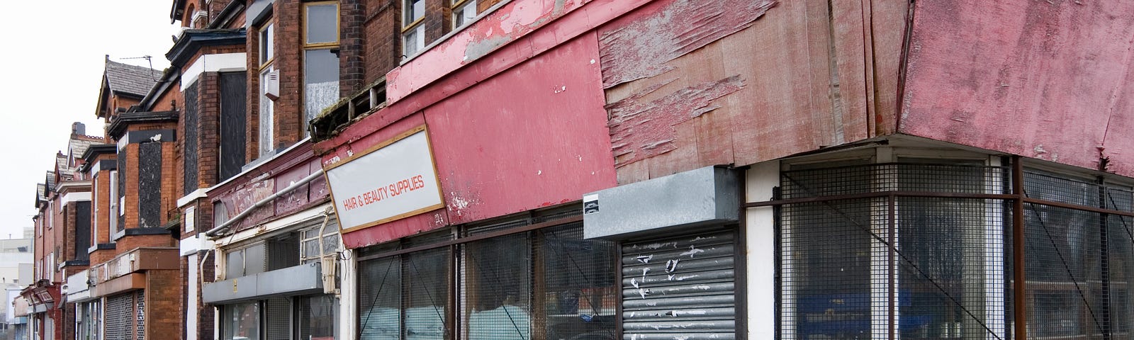 A row of shops that are boarded up on a street corner.