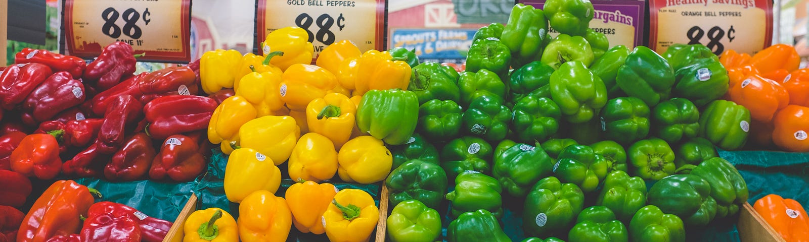 A display of red, yellow, green and orange peppers for sale at a supermarket for 88 cents.