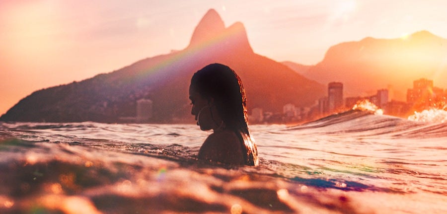 Woman swimming in ocean at sunset