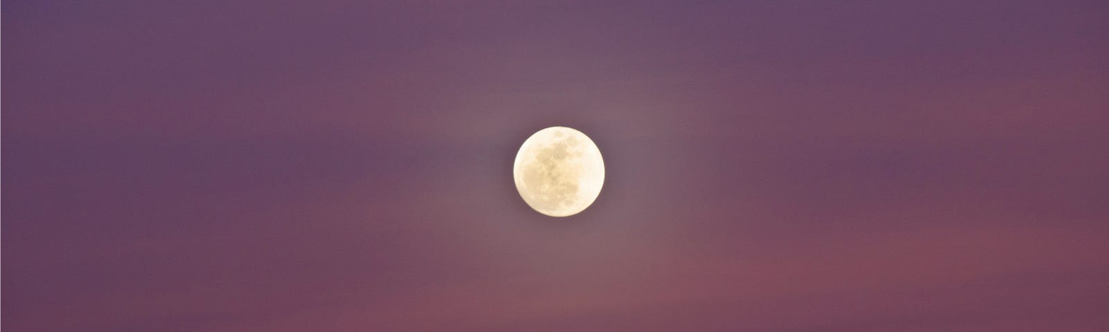 Full moon against pink-purple sky.