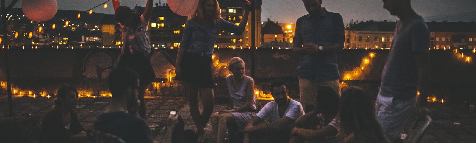 A photo of a rooftop party with garland lights.