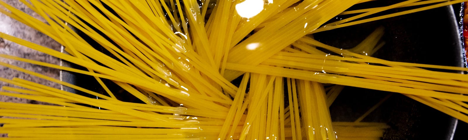 An overhead view of uncooked spaghetti in a pot of water.