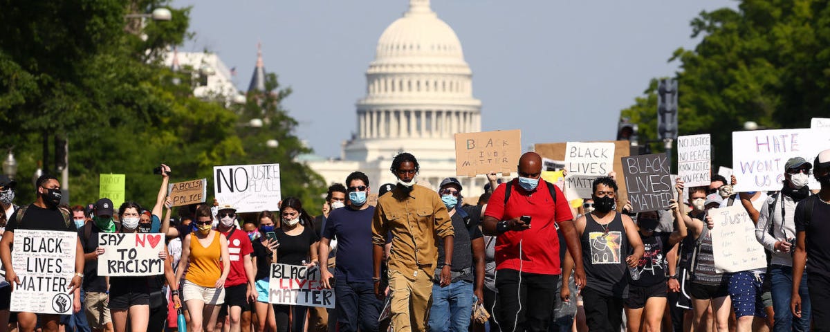 A crowd of pro-BLM protesters holding signs as they march down Pennsylvania Avenue away from the Capitol building in Washington, DC.