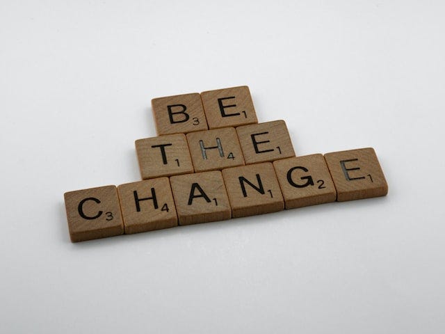 Scrabble tiles spell out “Be The Change”.