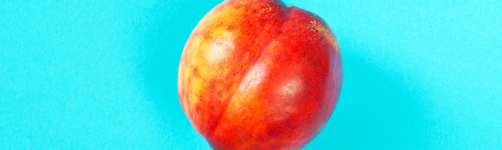 A photo of a peach against a cyan background.