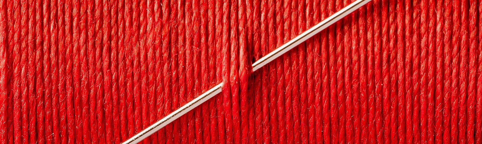 A needle stuck through a wall of red thread.