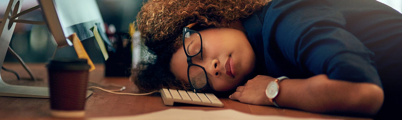 Exhausted Black businesswoman sleeping at her desk.