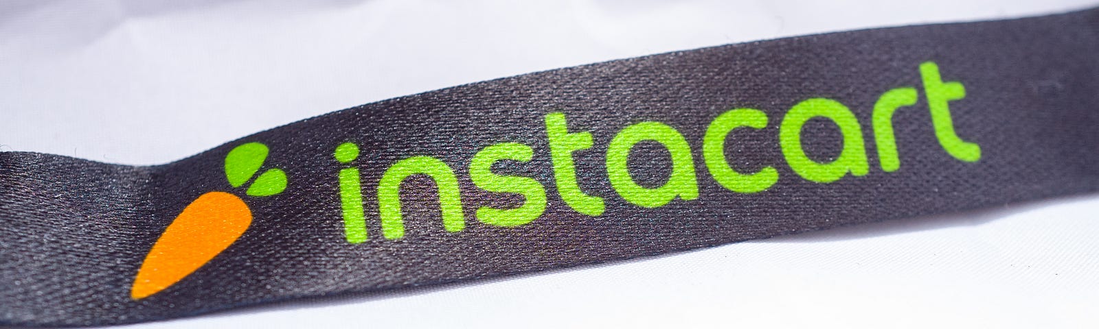 A photo of the Instacart logo on a lanyard against a white paper background.