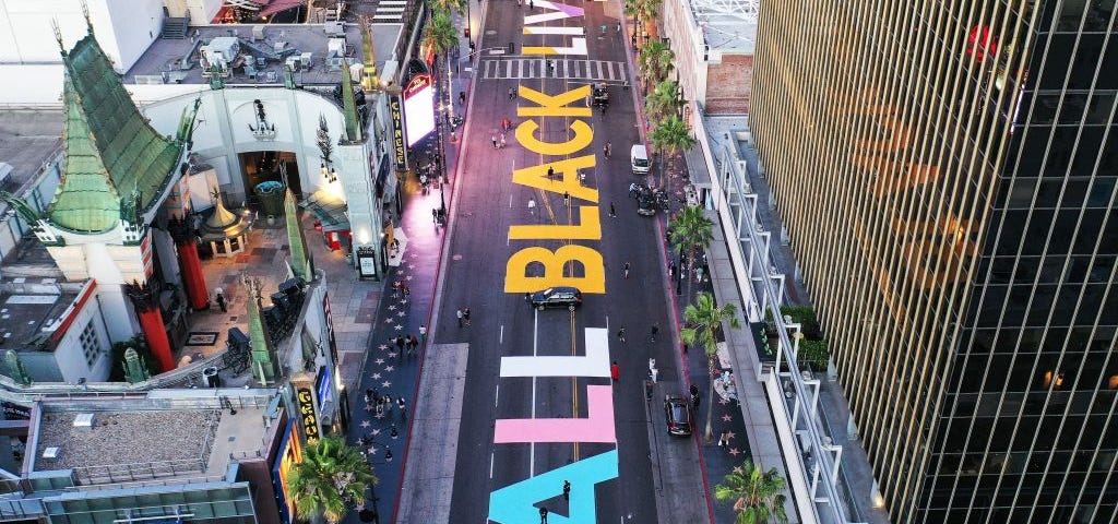 An aerial photo, presumably taken by drone, of protests in LA. “ALL BLACK LIVES MATTER” is painted on the road.