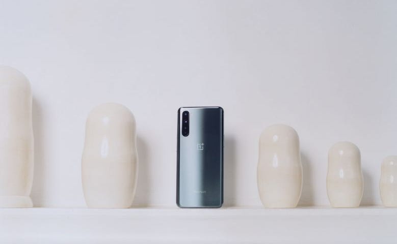 A promotional photo of a OnePlus Nord phone against a wall with cream-colored ceramics.