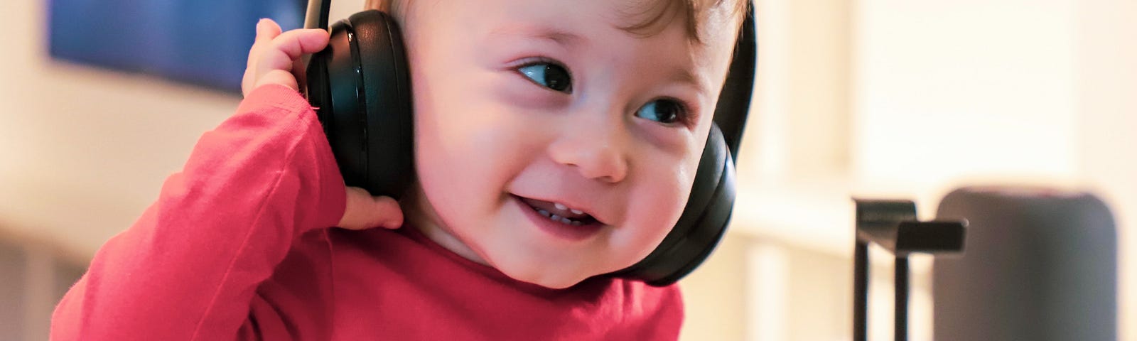 A baby puts a headset on and smiles.