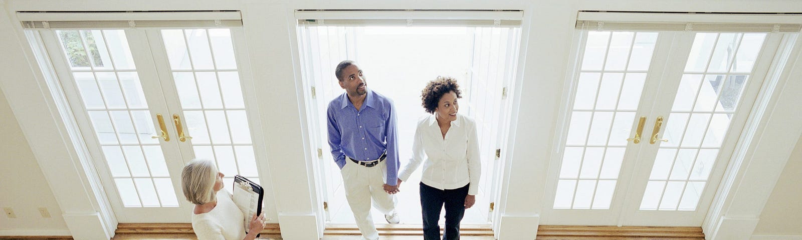 A couple with a real estate agent tour a home.