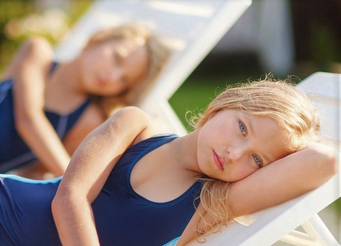 Twin girls. One is in the forefront and one behind, slightly blurred.