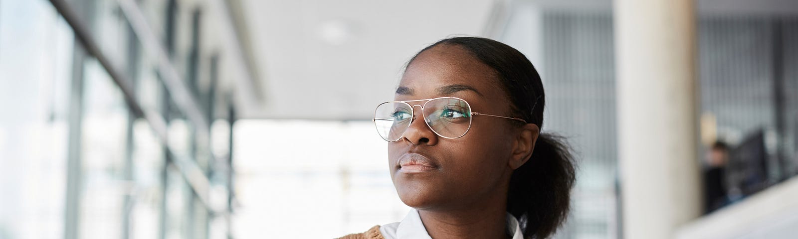 Black woman with serious expression working on her laptop, looking out the window.