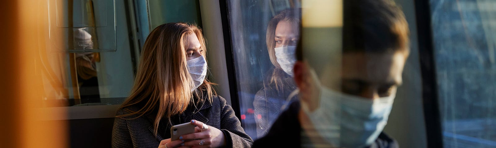 Young people on train wearing face masks.