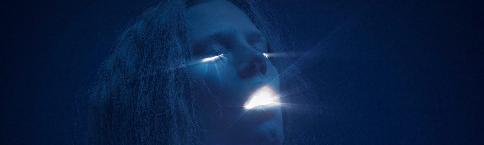 A photo of a woman with light shining from her eyes and mouth. The image is a dark blue/black shade.