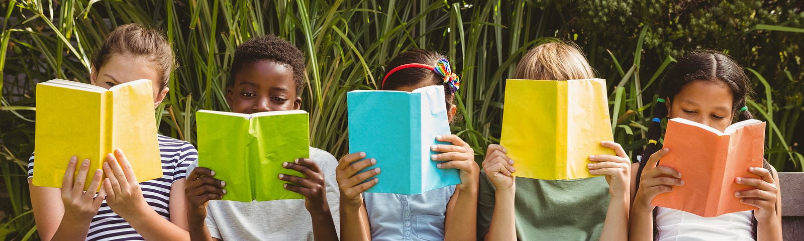 Children reading books at a park.