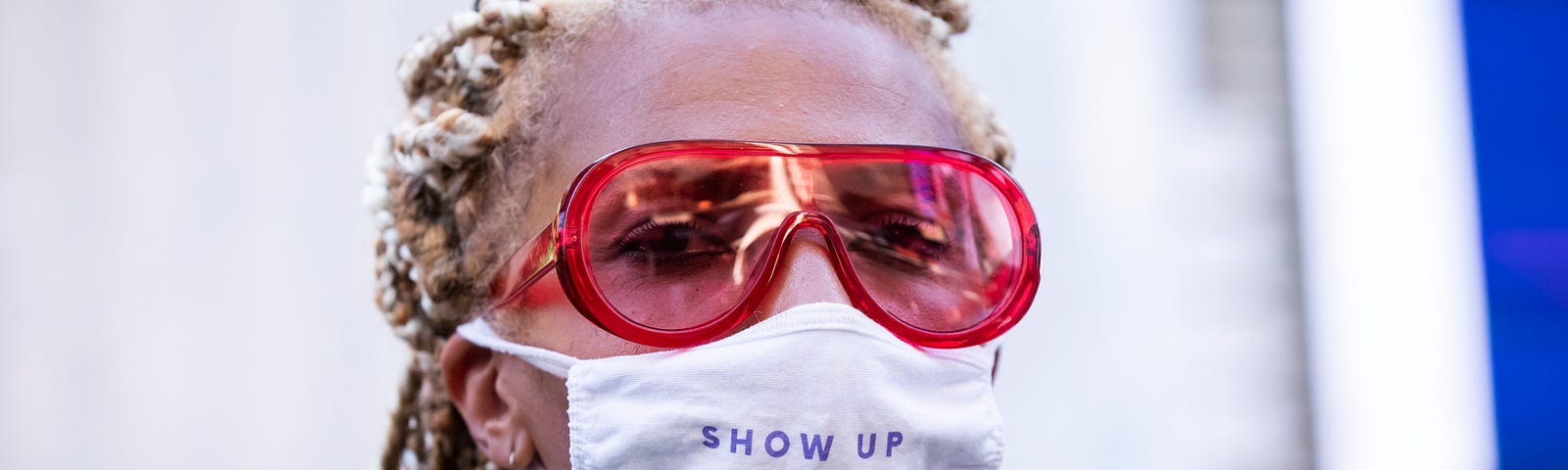 Black woman wearing a face mask that says “Show up for Black women.”