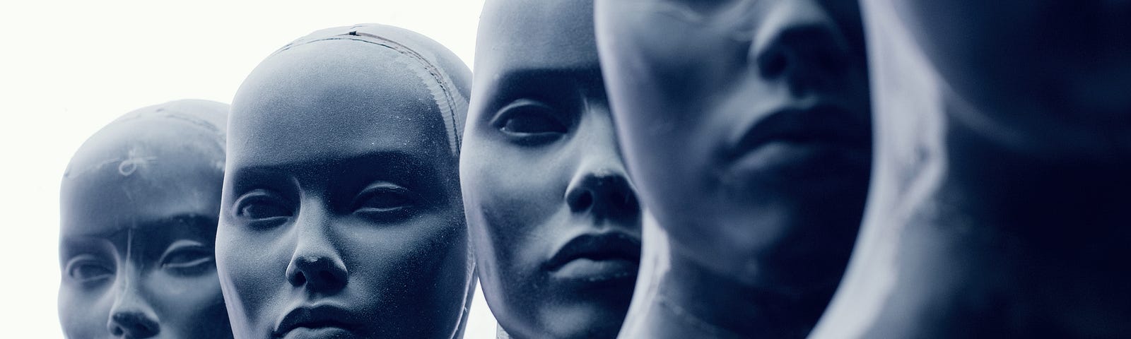 A photo of five sculpture-like human faces.