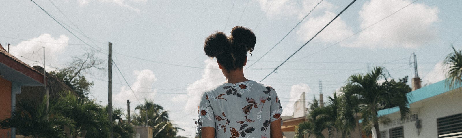 Back view of a young woman walking down a street.