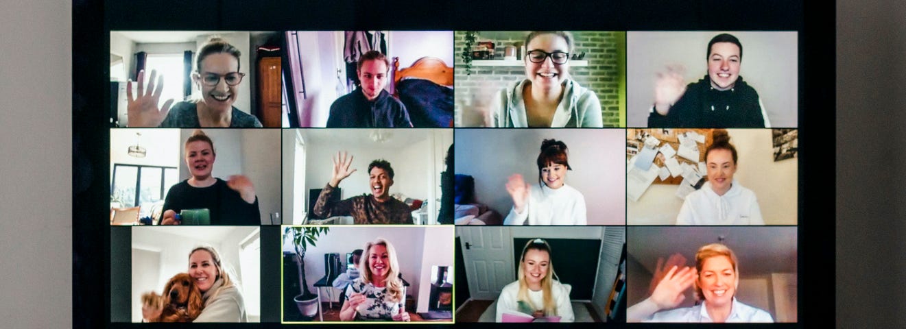 Friends waving to each other during a large video conference call on a computer screen.