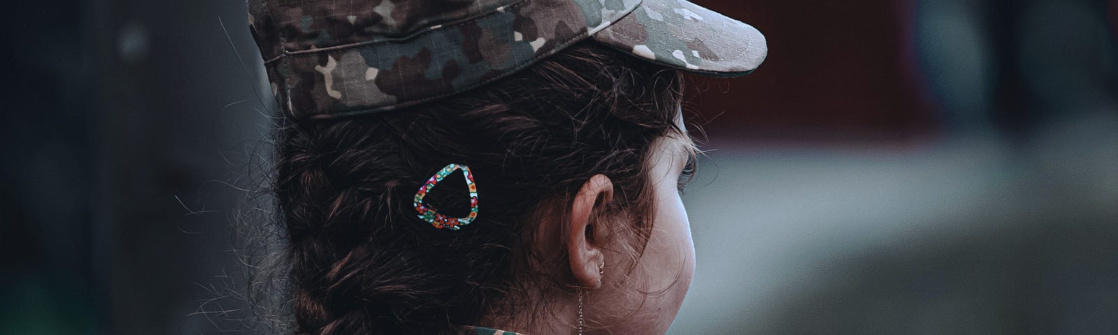 A short woman in fatigues faces away from the camera