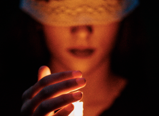 Portrait of a woman protecting a candle with her hand