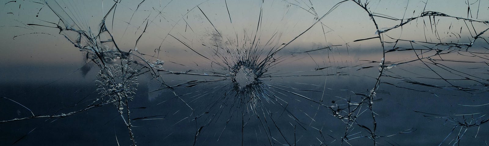 A bullet hole in glass shows an ocean in the background