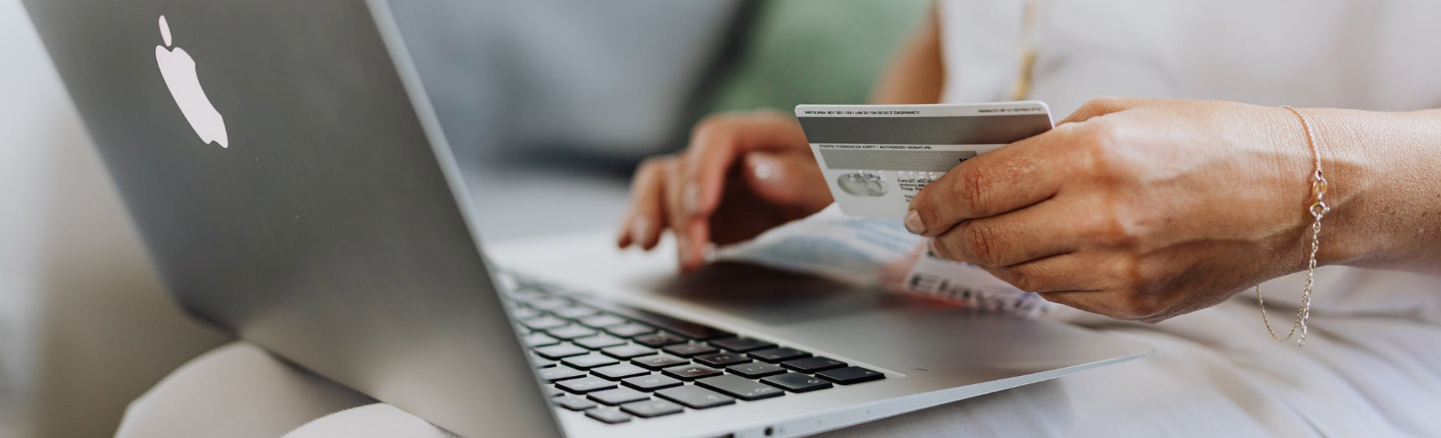 Person holding credit card while on laptop.