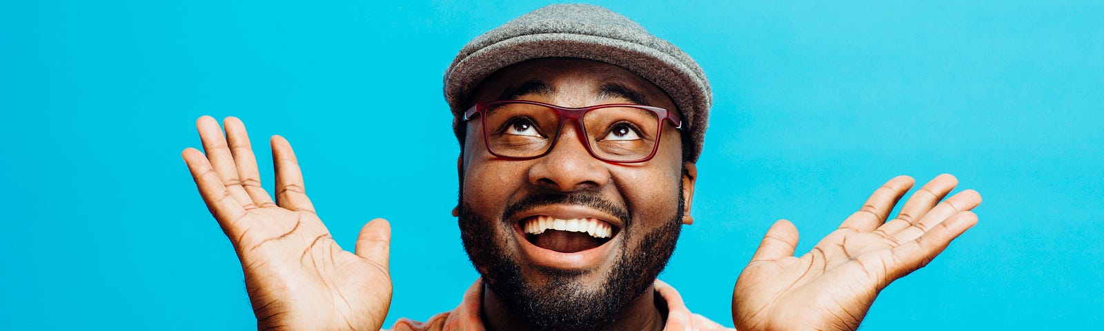 A photo of a man smiling with his eyes looking up towards the sky, jazz hands and all.