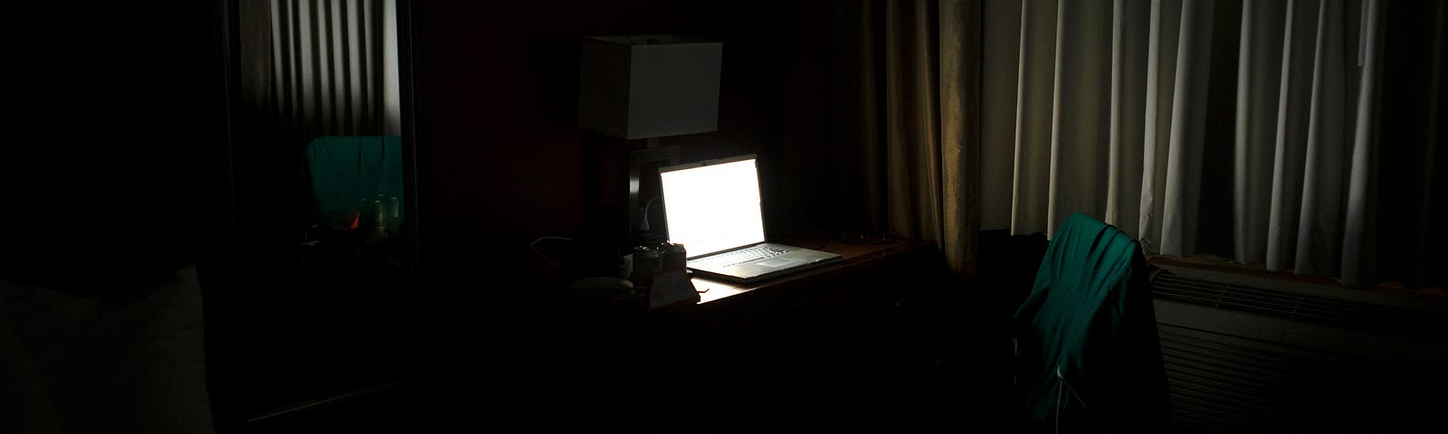 Only a bright laptop screen is visible in this dark room.
